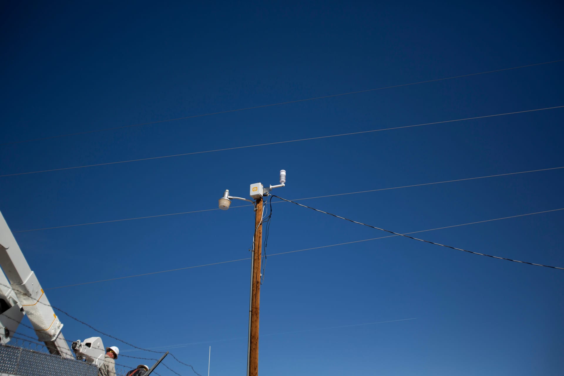 WatchPost weather station mounted on a power line under a clear blue sky