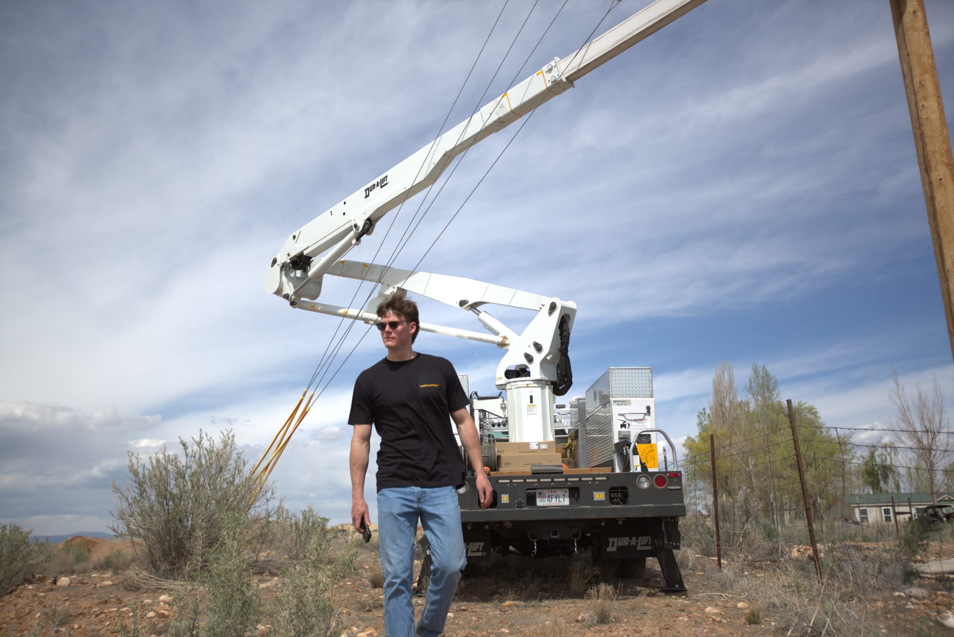 A WatchPost team member walking past a bucket truck at a rural installation site
