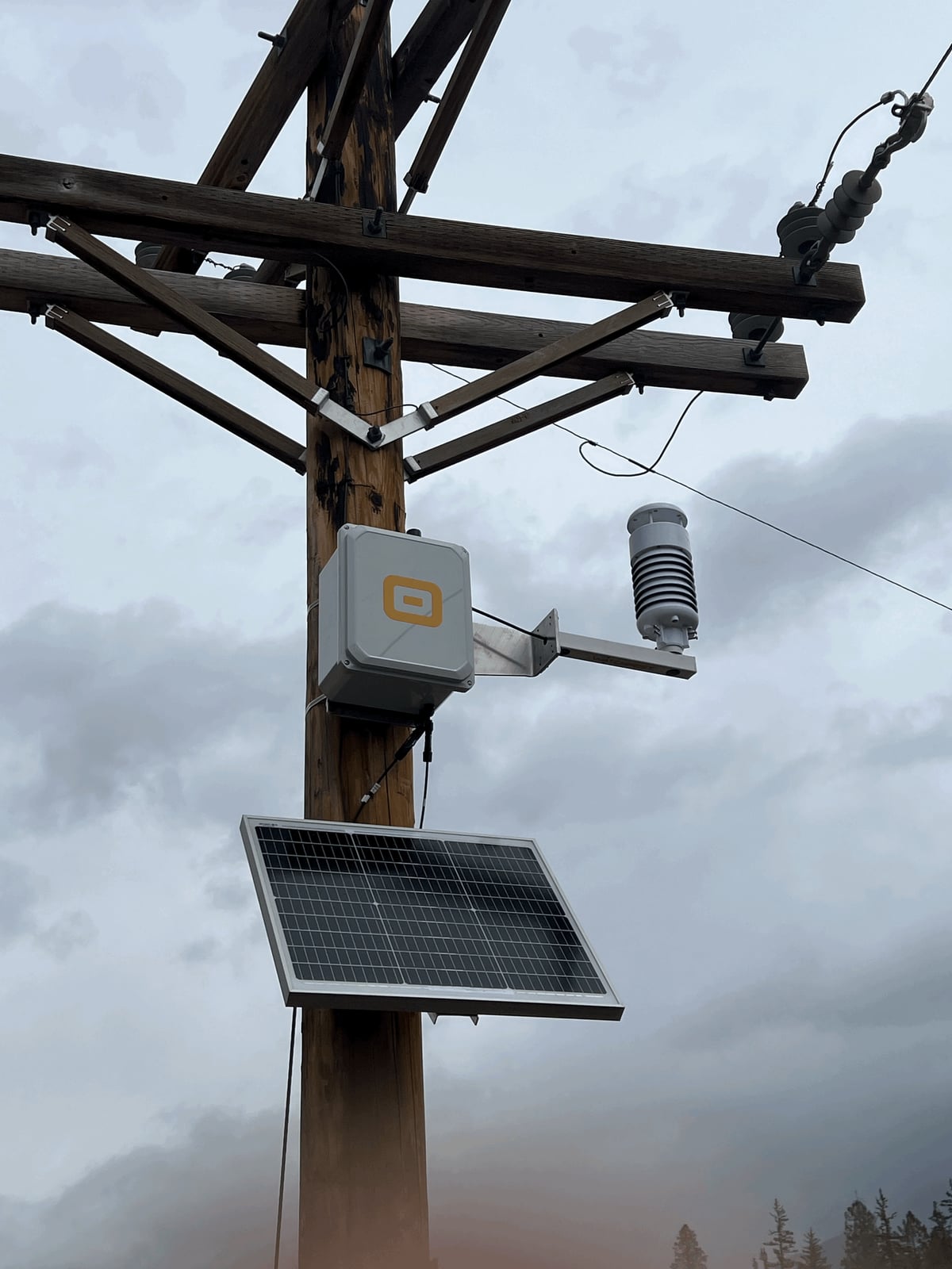 Solar-powered WatchPost sensor unit mounted on a utility pole against a cloudy sky