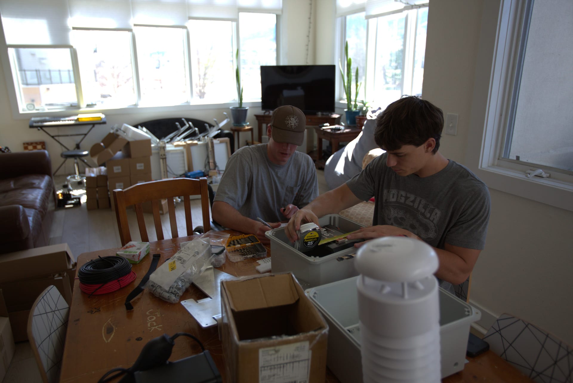 Two WatchPost builders assembling weather-station hardware at a workbench